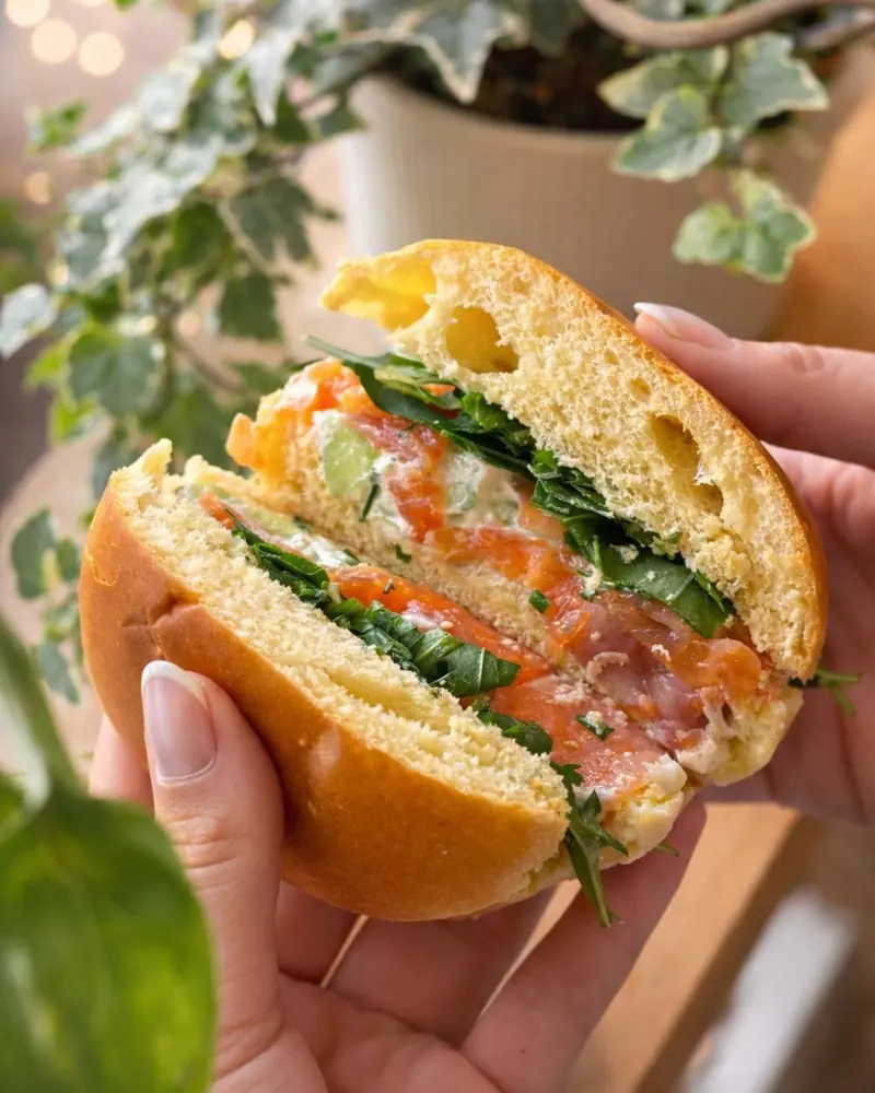Sandwich brioché à la truite fumée tenu en main